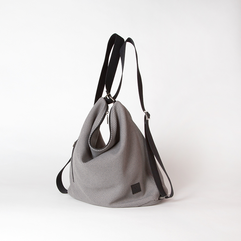 Tasche aus Ozean Plastik in hellem braun mit schwarzen Applikationen als Rucksack getragen